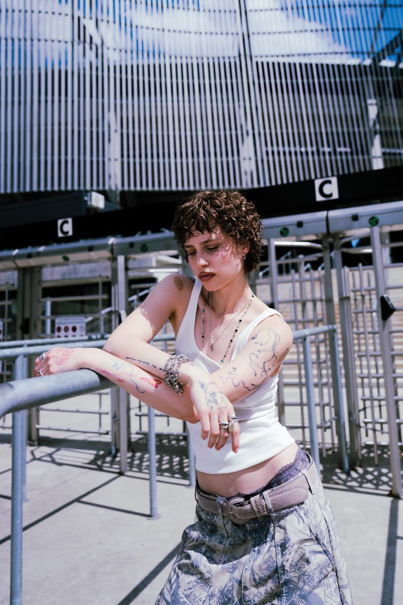 White tank at the turnstiles – thin necklaces, first fineline pieces on the arms.