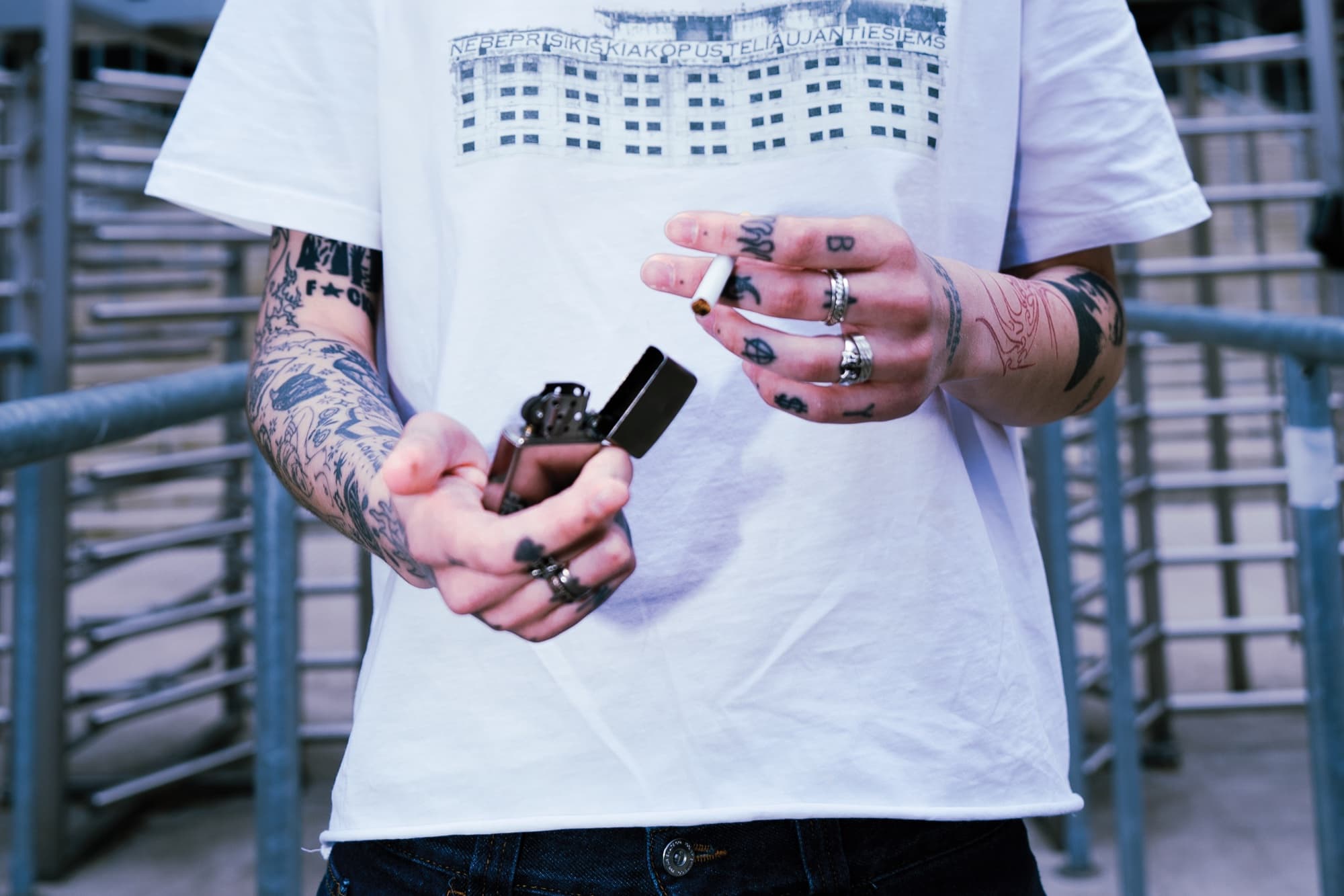 White tee with the housing-block print – knuckle letters and silver rings.