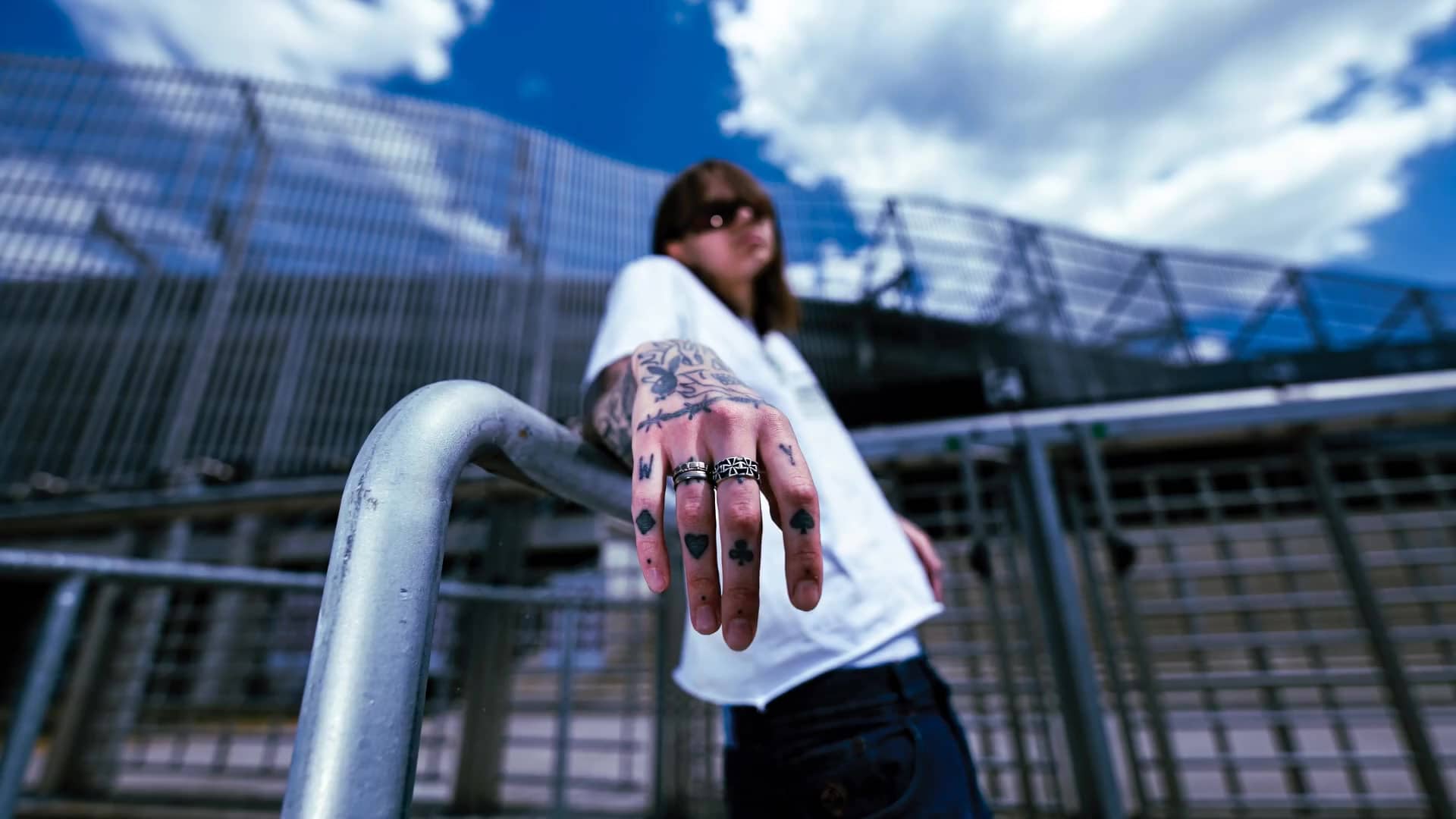 Tatuiruota ranka, ištiesta į objektyvą, sviedžia kauliukus į kamerą.